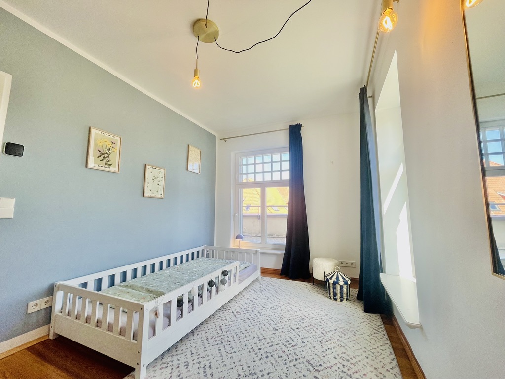 Schlafzimmer mit Gitterbett und Parkett